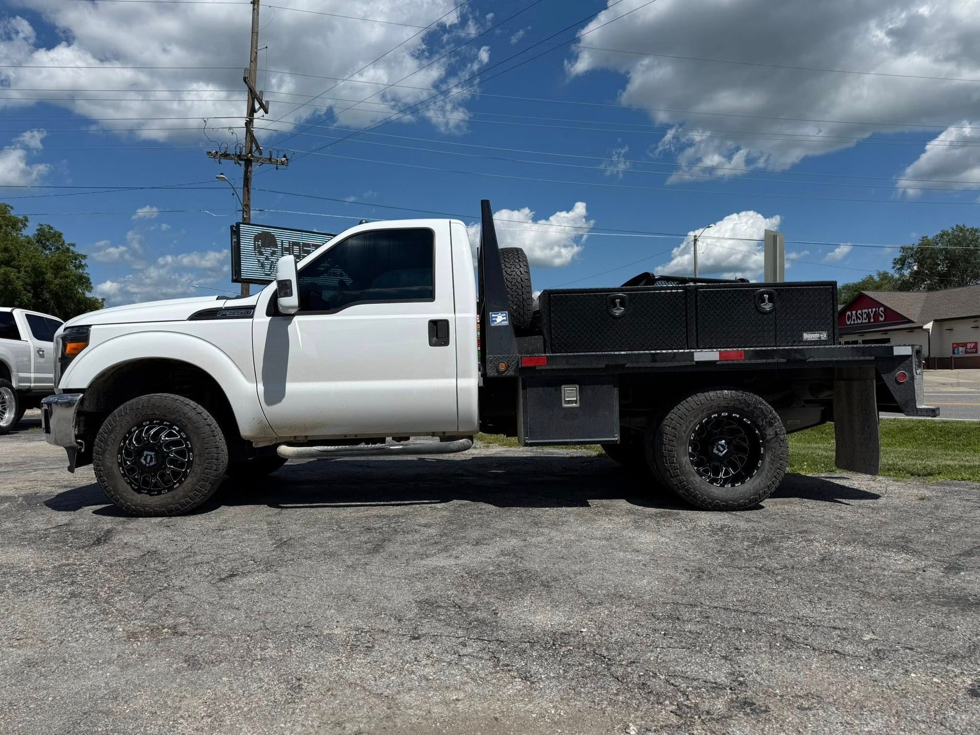 A white truck with a flatbed is parked in a parking lot.