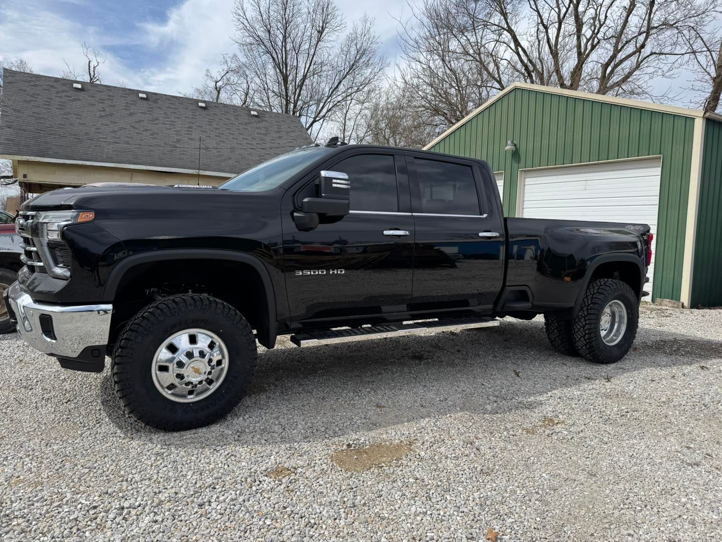 A black truck is parked in front of a green garage.