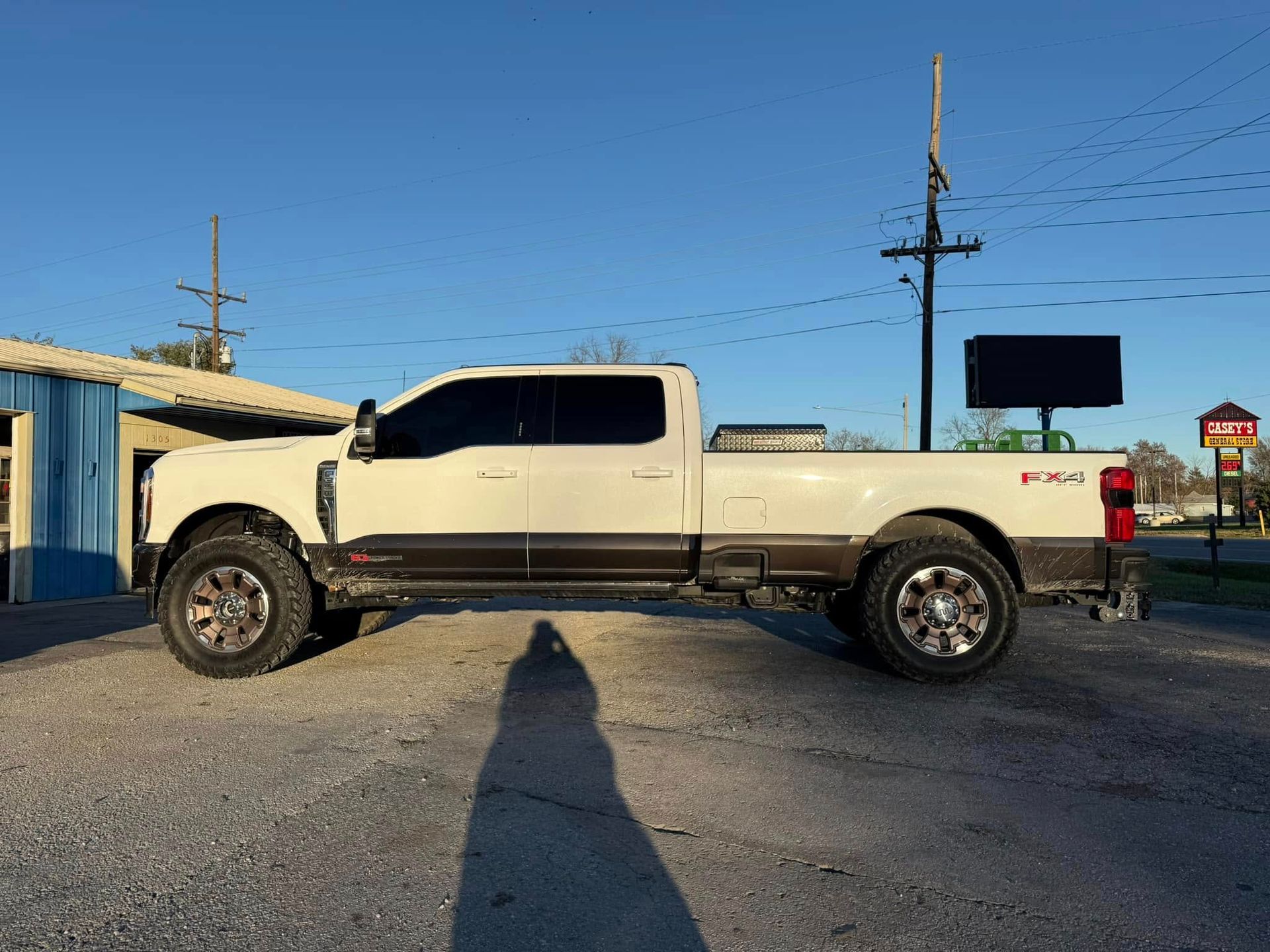 A white truck is parked in a parking lot next to a building.