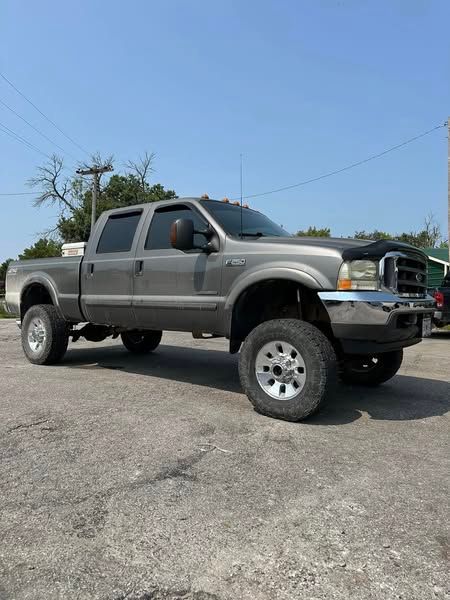 A gray ford f250 pickup truck is parked in a parking lot.
