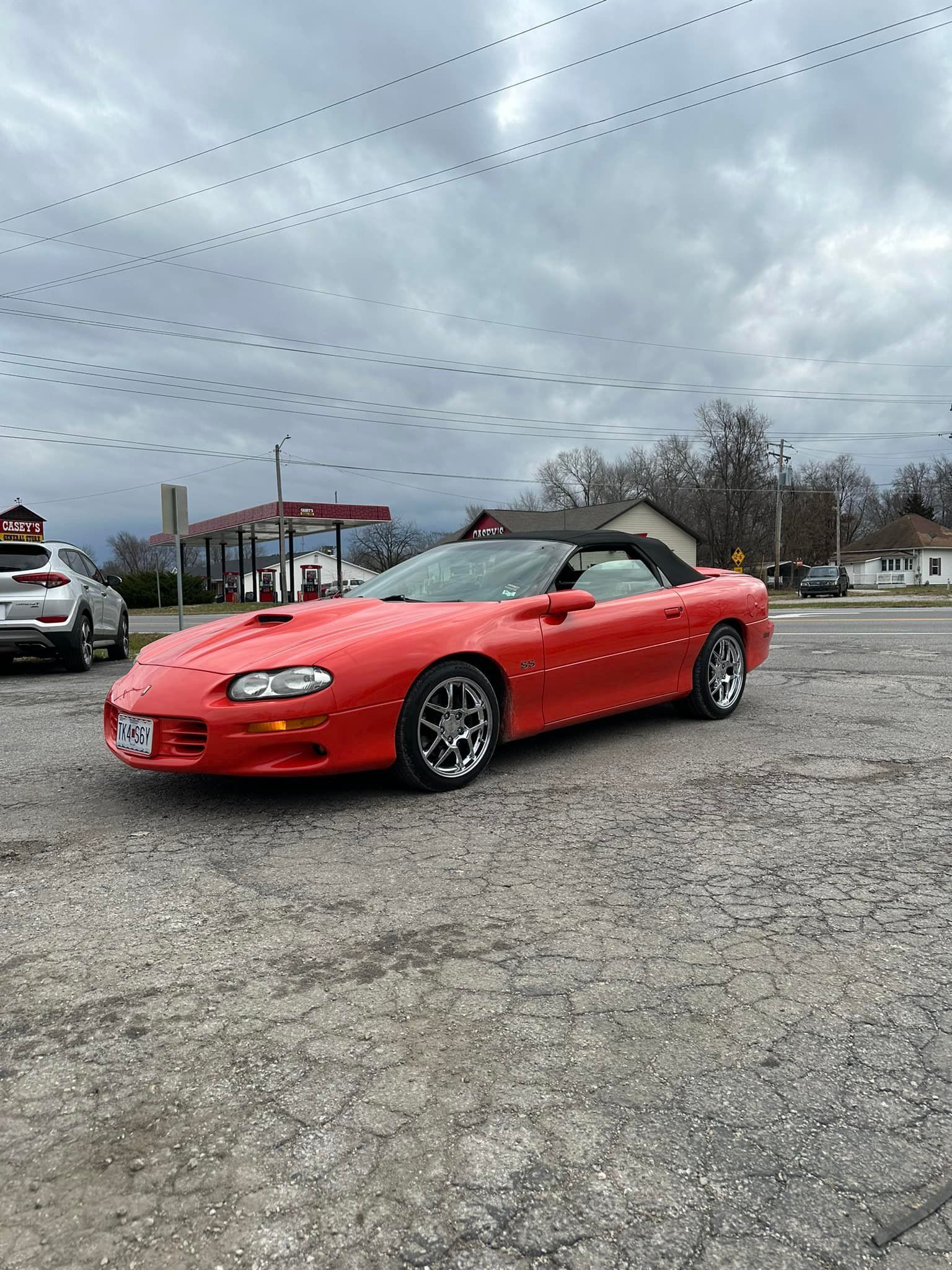 A red convertible chevrolet camaro is parked in a parking lot.