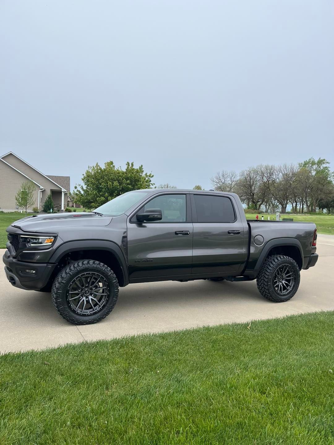A ram truck is parked in a driveway in front of a house.