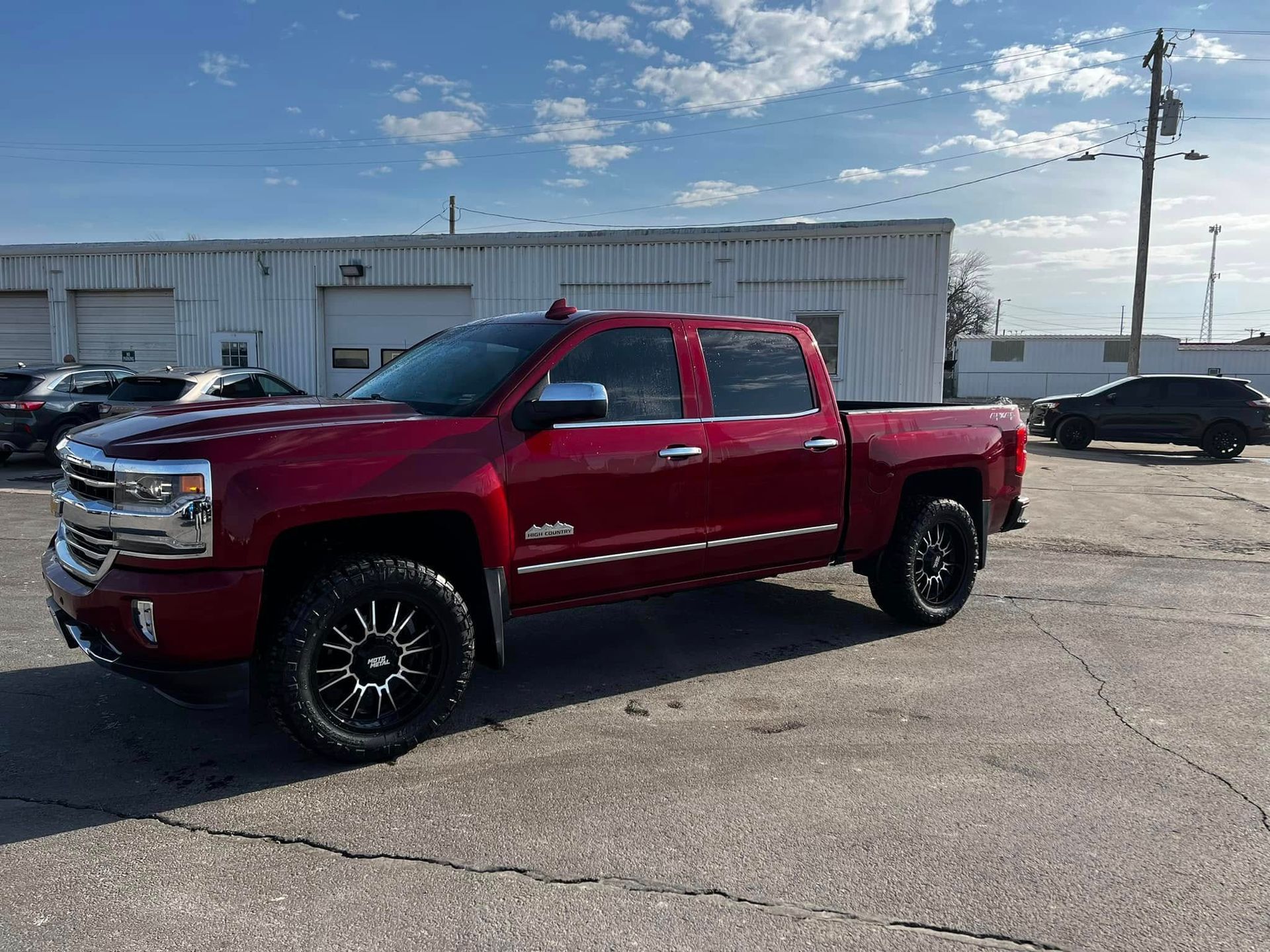 A red truck is parked in a parking lot in front of a building.