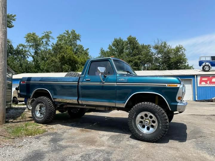 A blue pickup truck is parked in front of a garage.