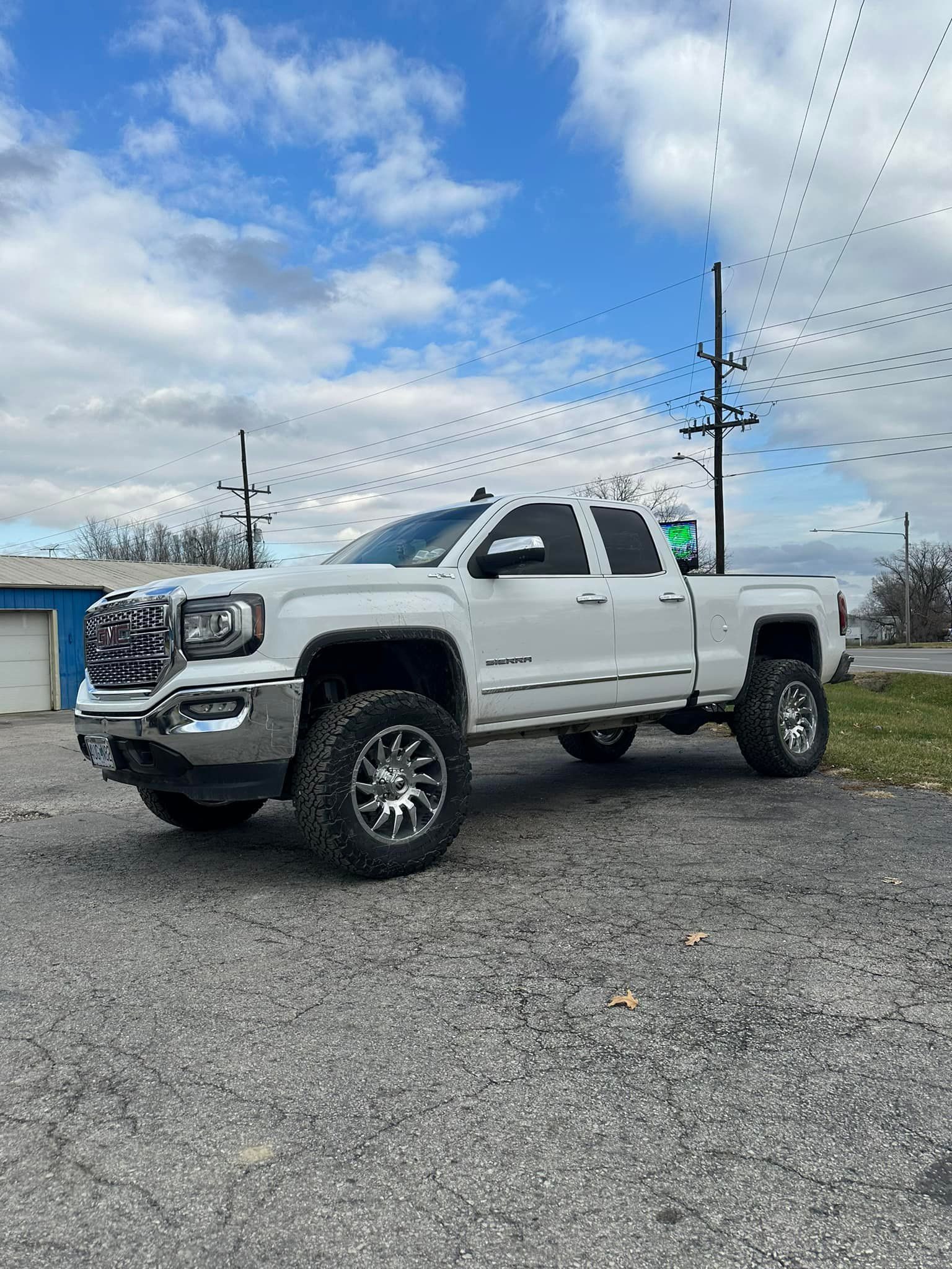 A white pickup truck is parked in a gravel lot.