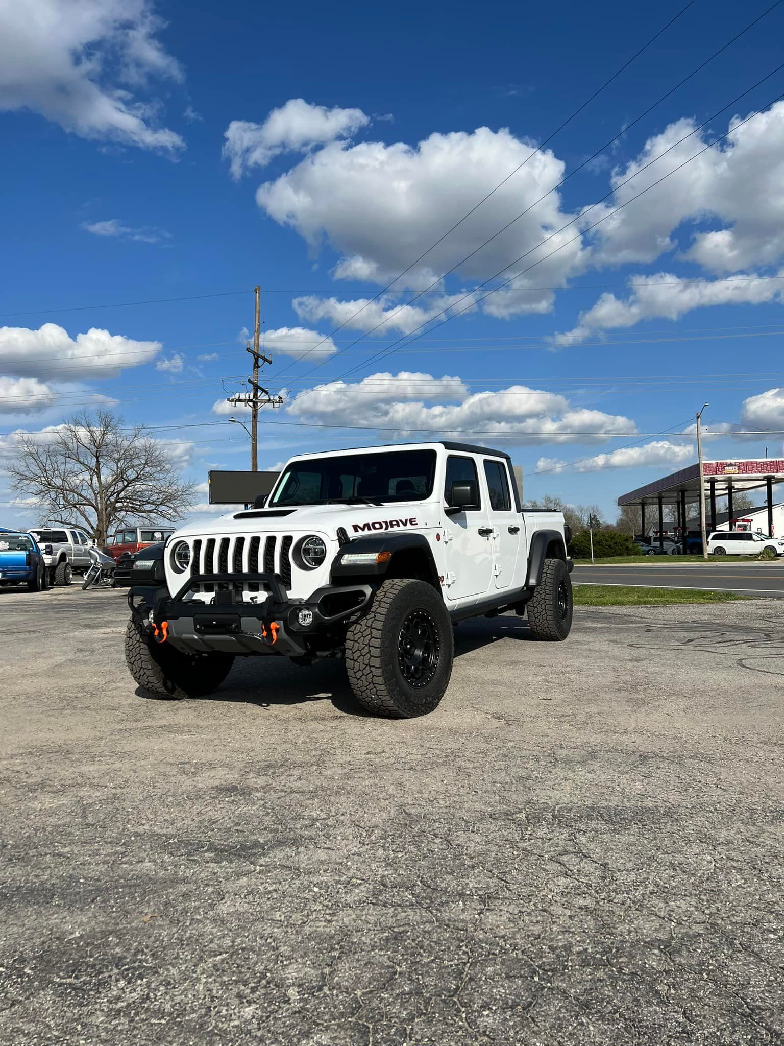 A white jeep is parked in a gravel lot.