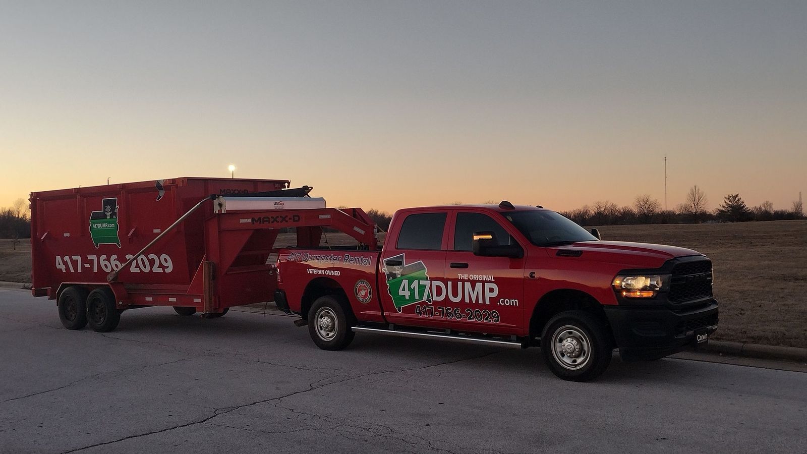 A red truck with a trailer attached to it is parked on the side of the road.