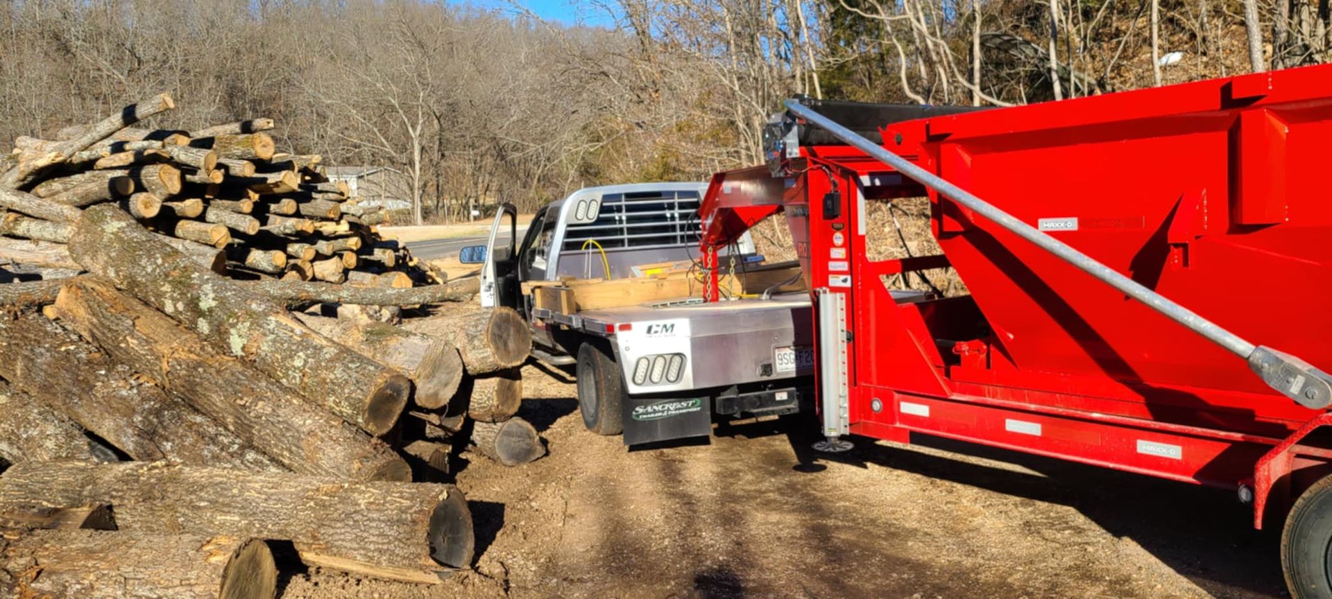 A red dump truck is being towed by a white truck.