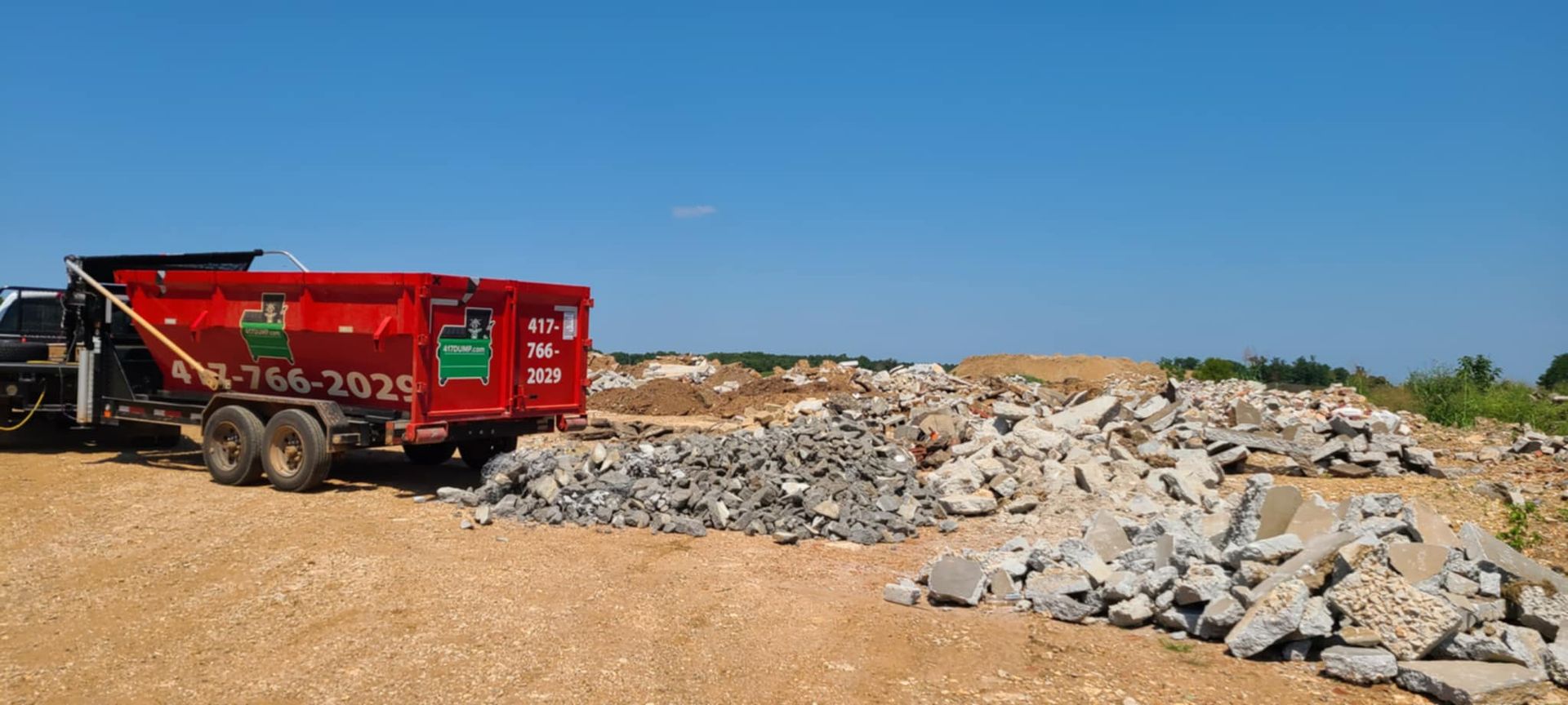 A red dump truck is parked in a pile of rocks.