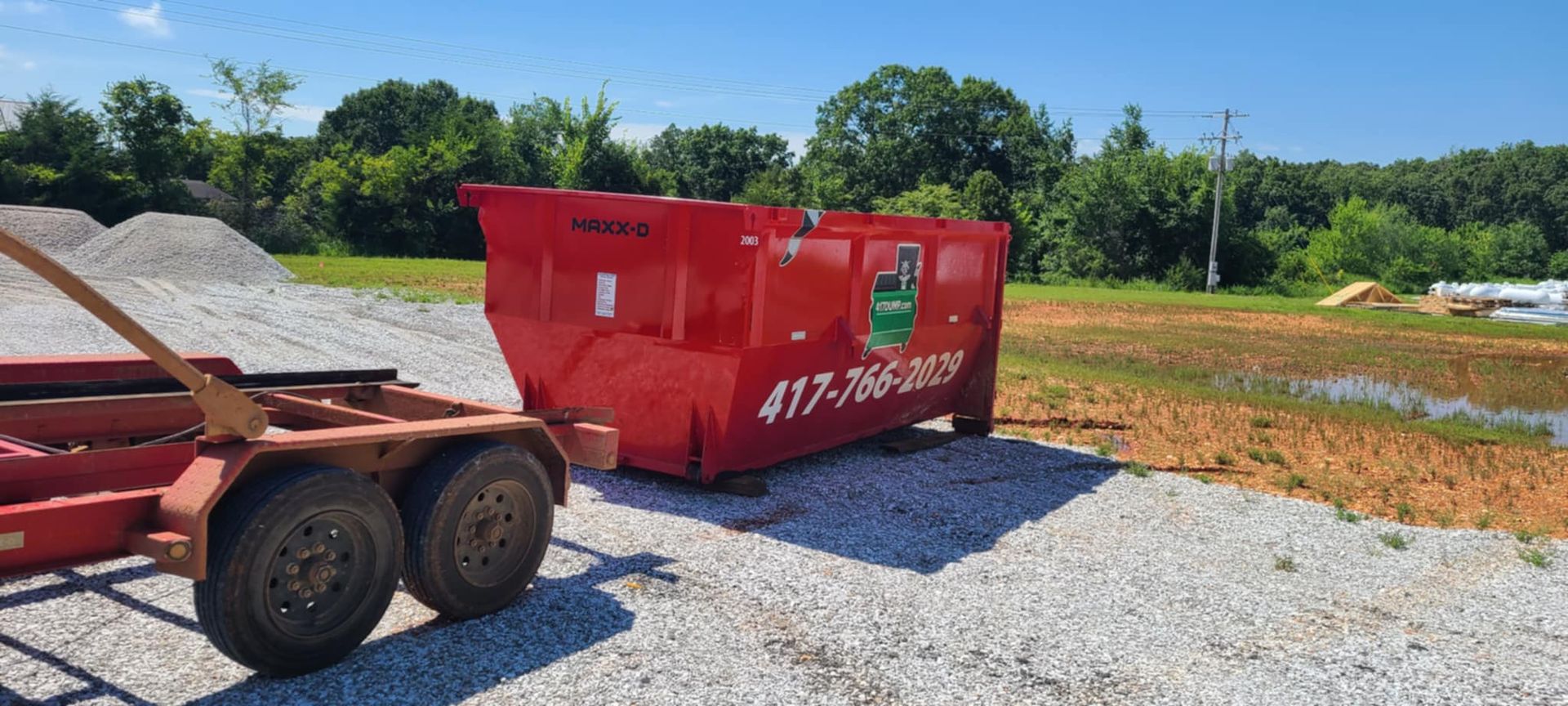 A red dumpster is sitting on top of a trailer.