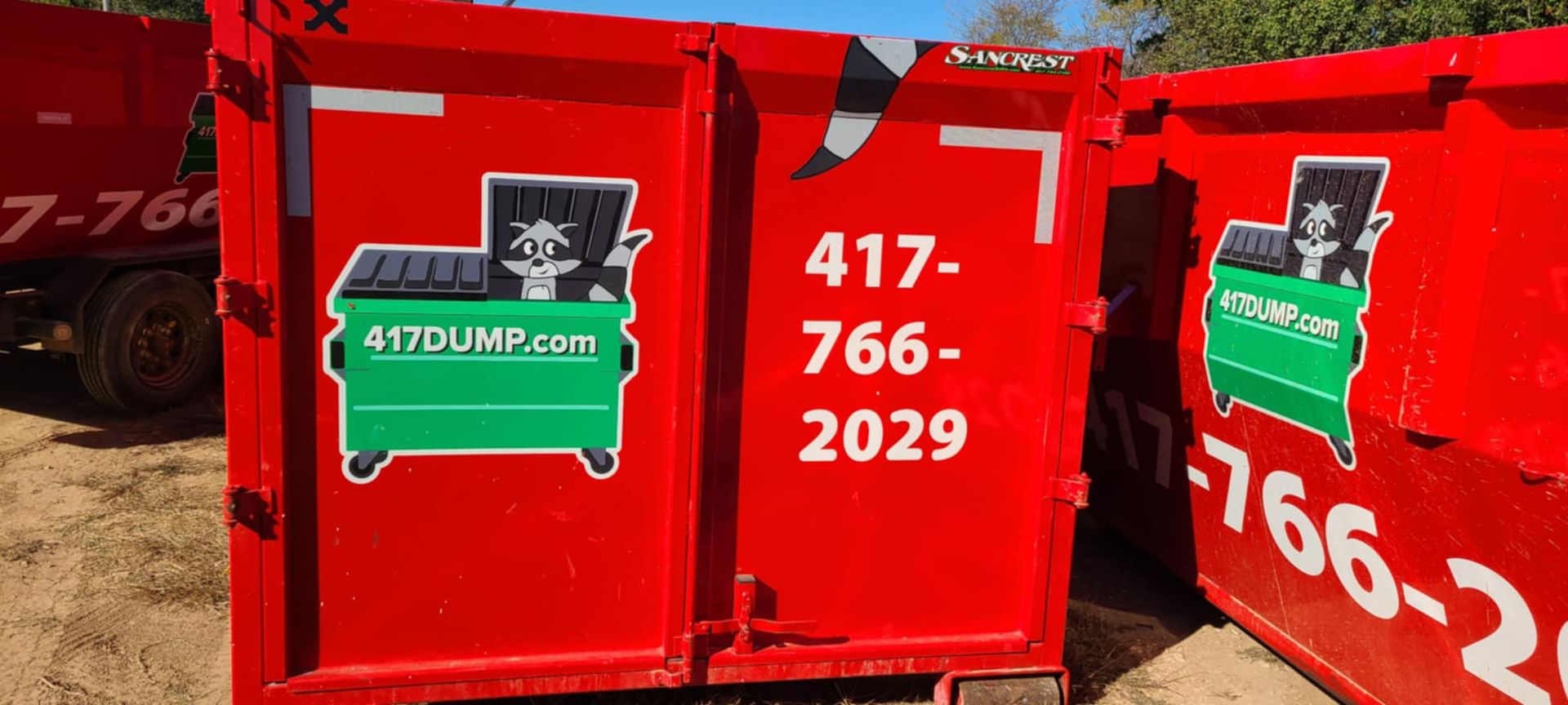 A group of red dumpsters are parked next to each other.