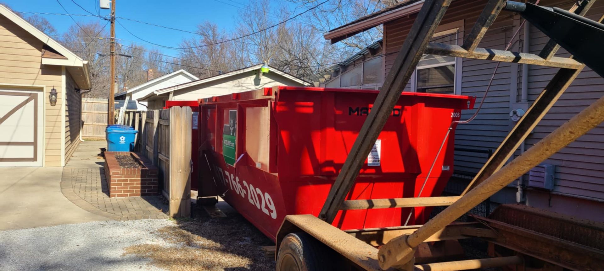A red dumpster is sitting in front of a house.