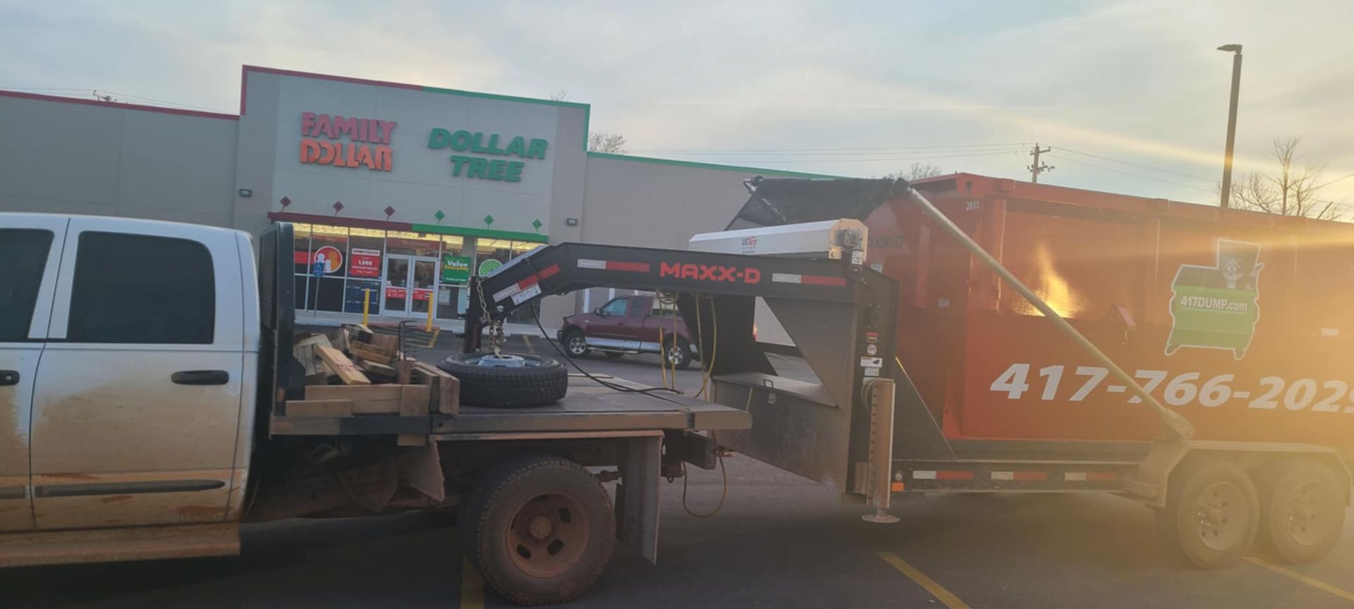 A dumpster on a trailer is parked in front of an establishment.