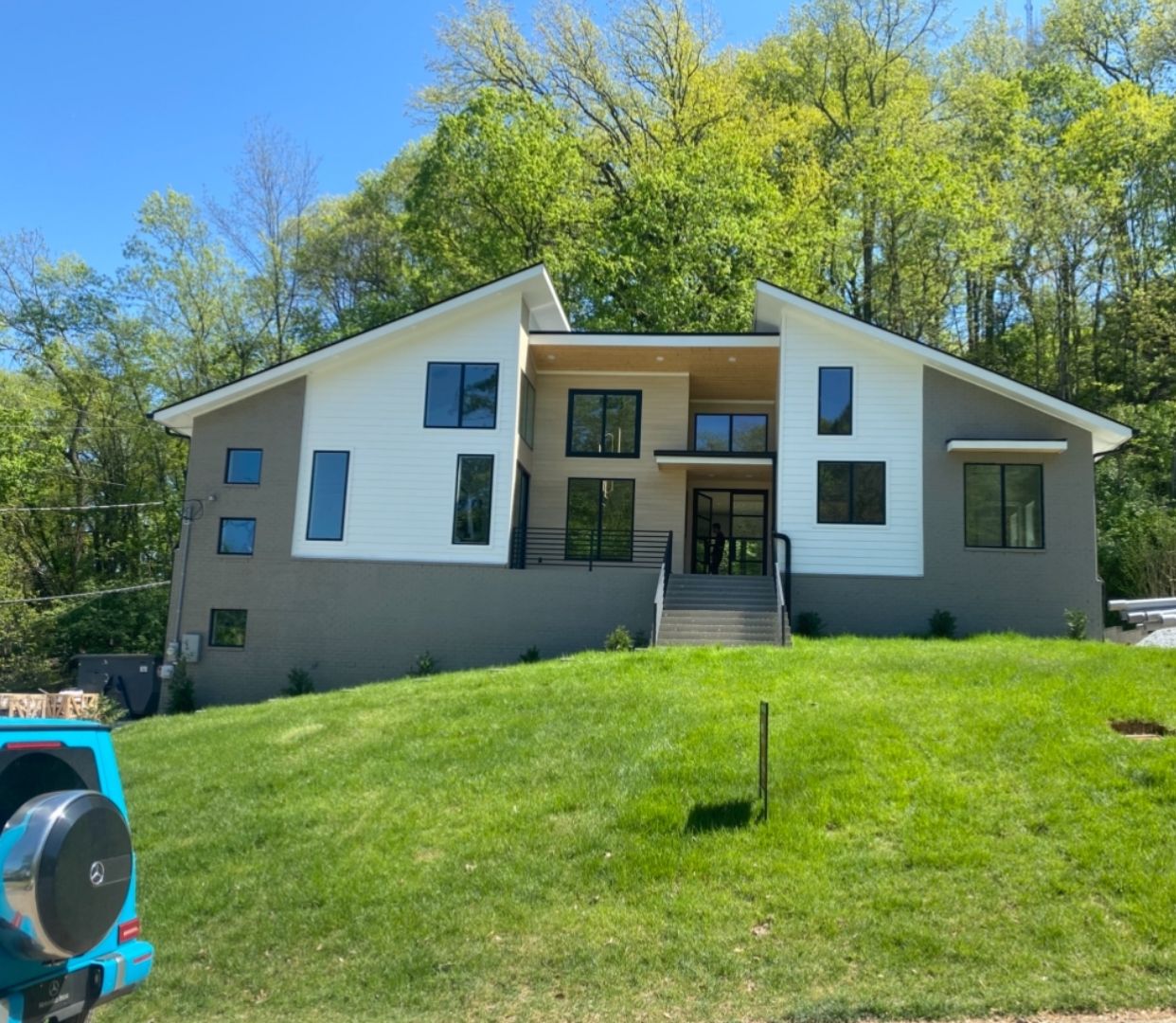 A large house is sitting on top of a lush green hillside surrounded by trees.