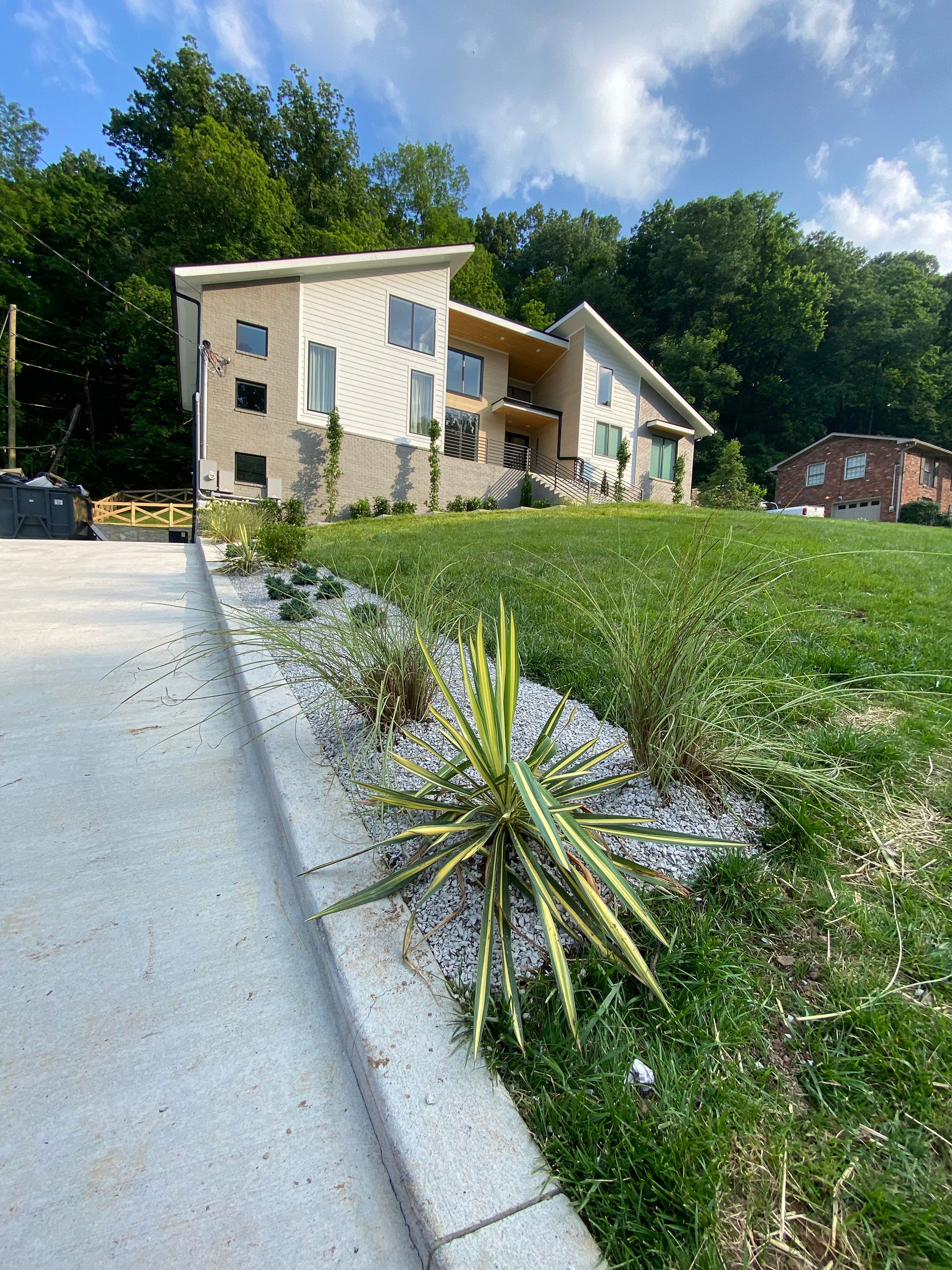 A large house is sitting on top of a lush green hillside.