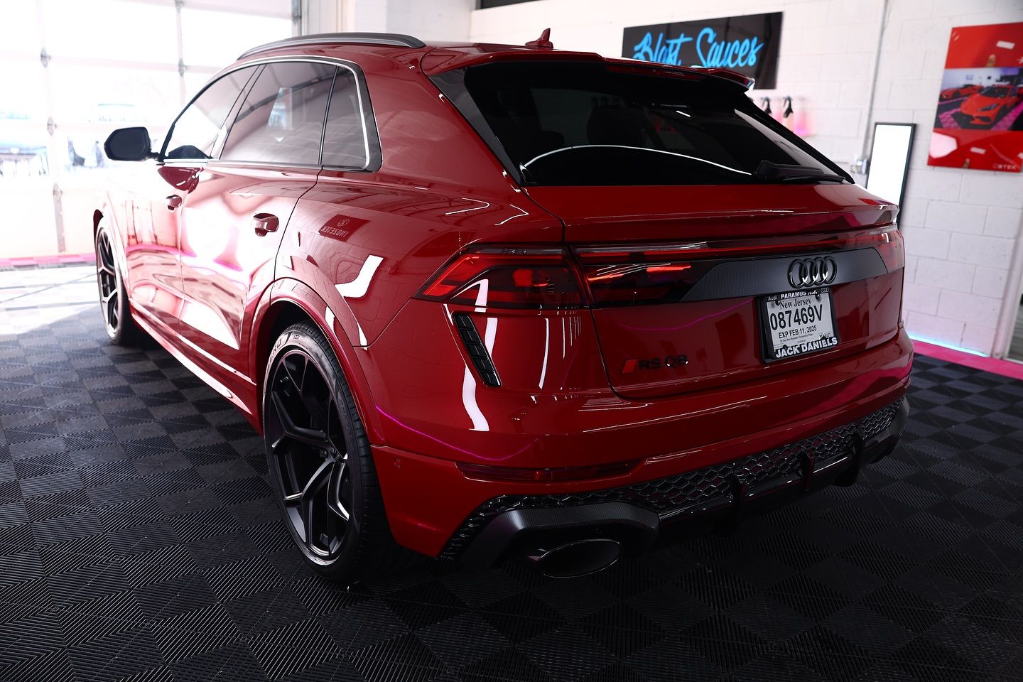 Red Audi SUV, black wheels, parked inside on textured black flooring.