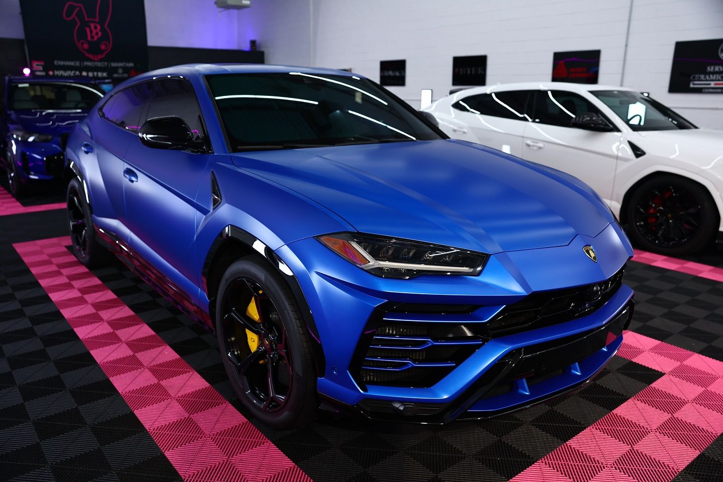 Blue Lamborghini Urus SUV, black accents, yellow brake calipers, indoors.
