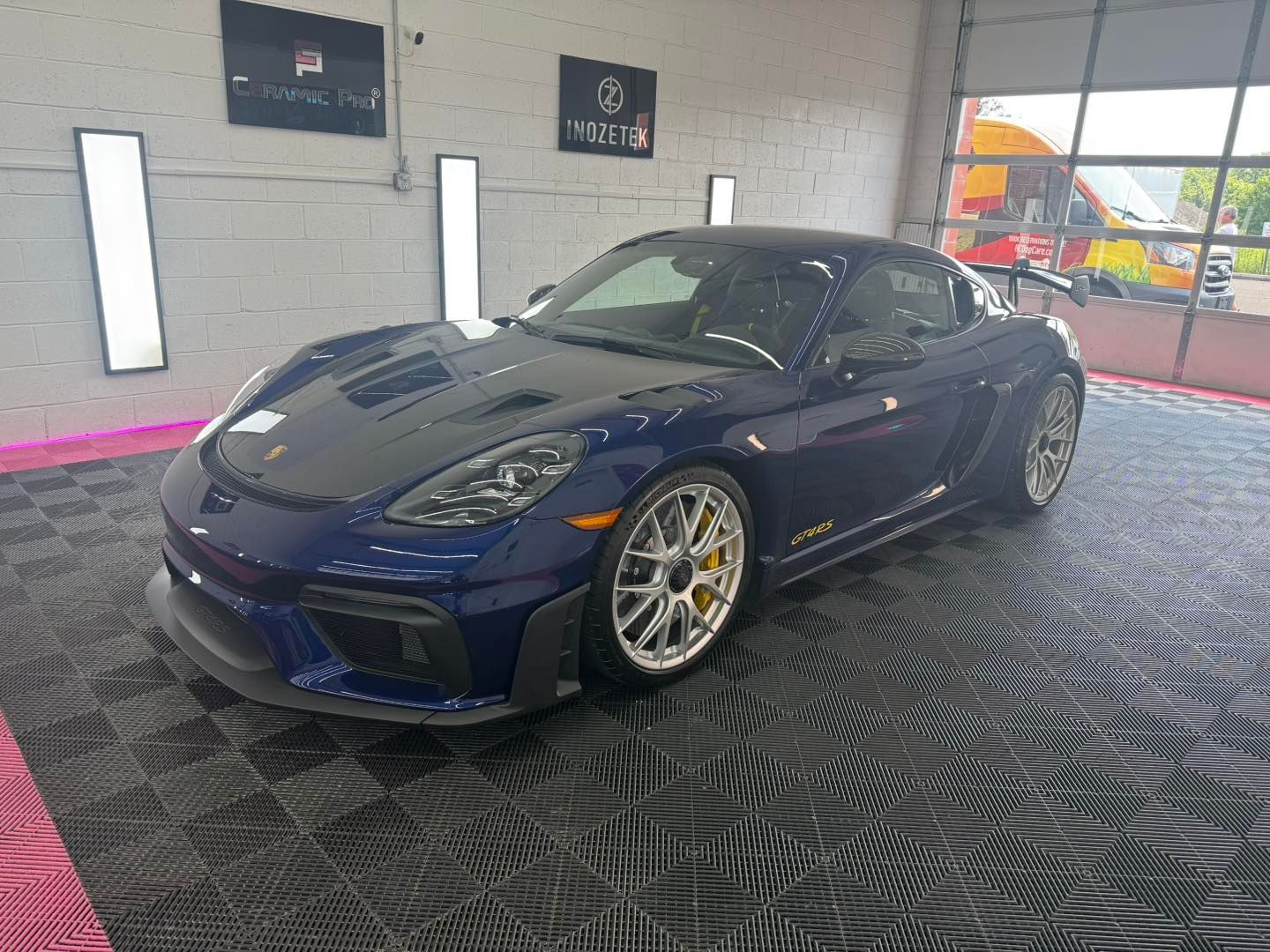 Blue Porsche sports car in a garage with a black floor.