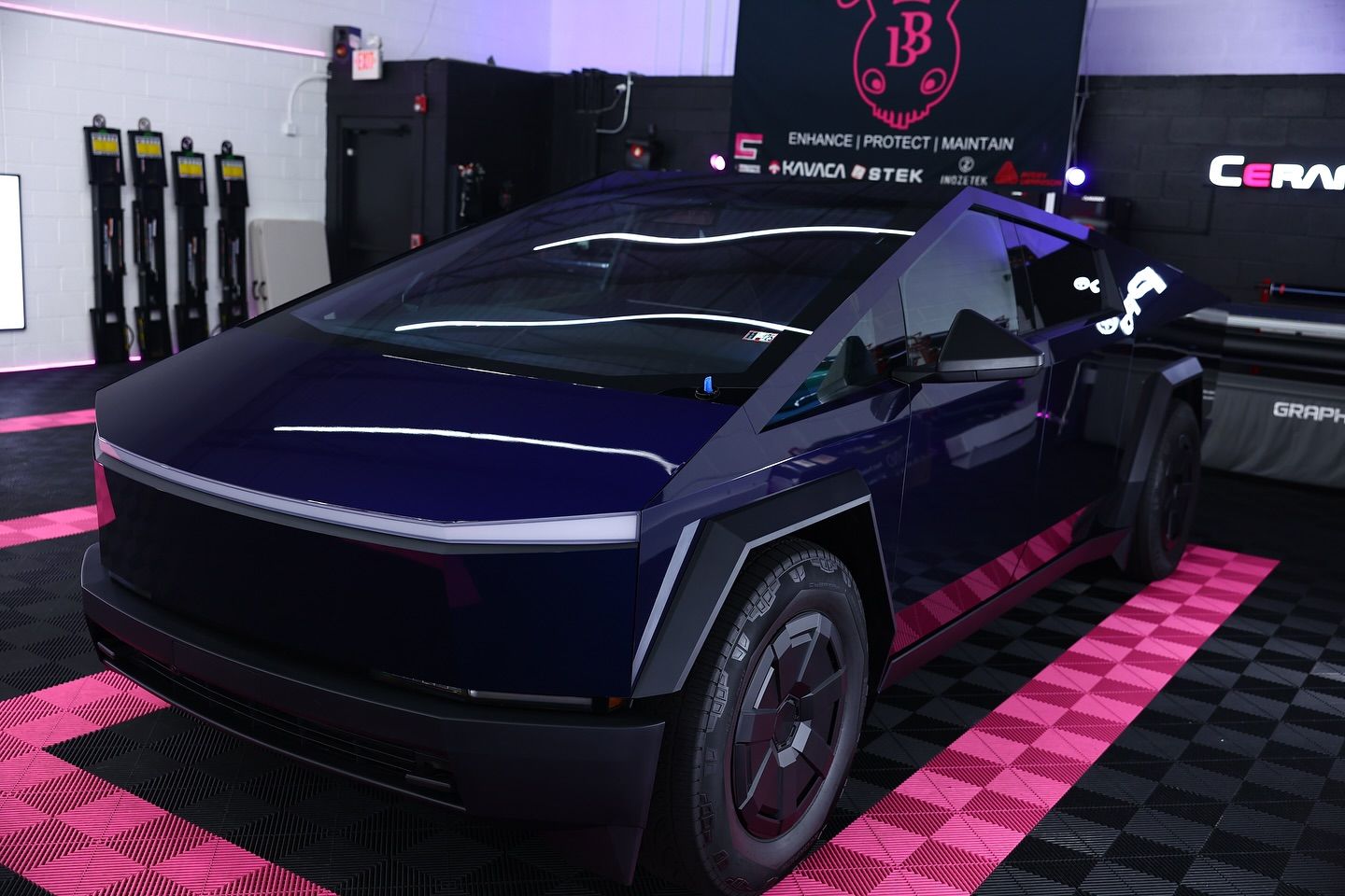 Dark blue Tesla Cybertruck on pink and black tiled floor, inside a shop.