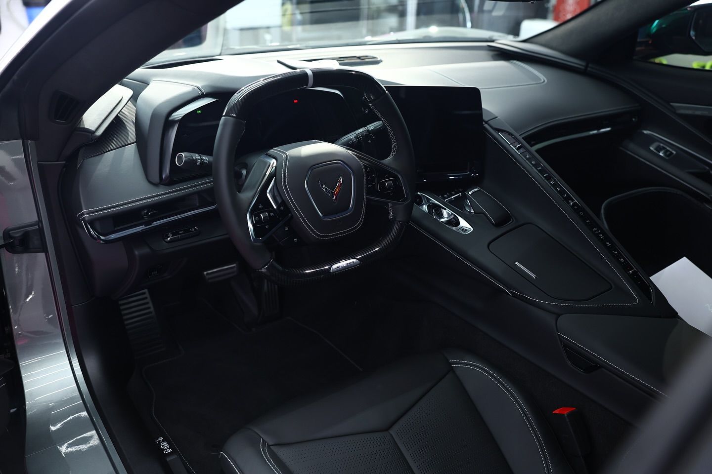 Interior view of a black Corvette, showing the steering wheel, dashboard, and seats.