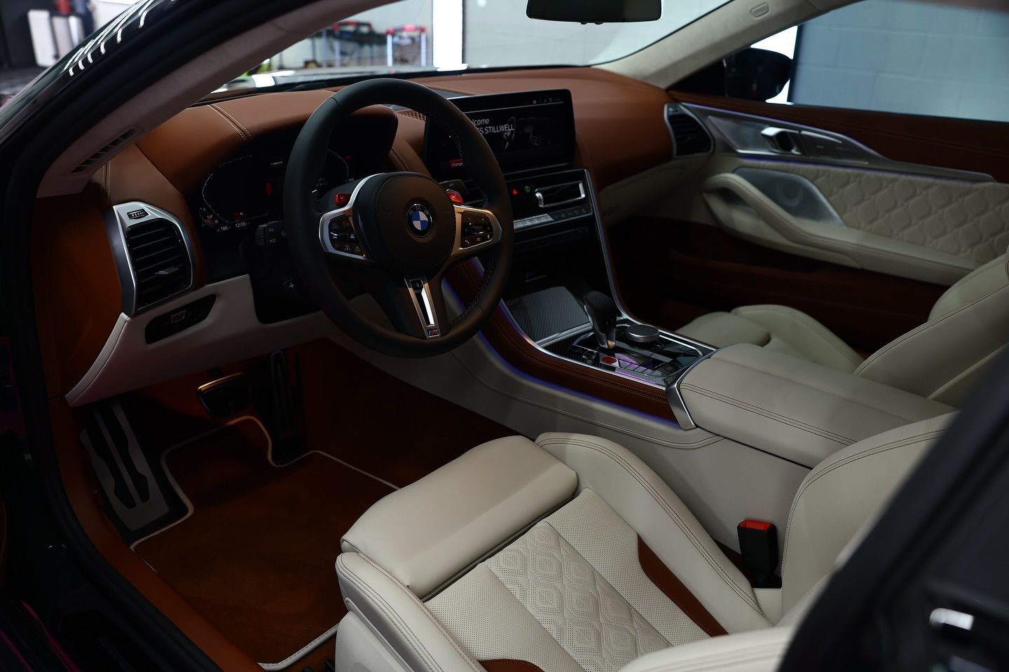 Tan and white interior of a BMW with a brown dashboard, steering wheel, and seats.