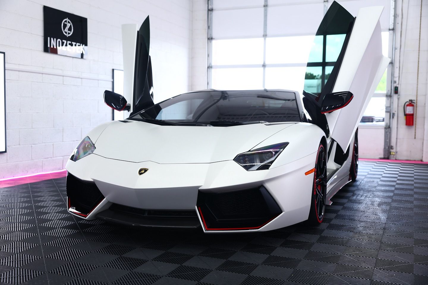 White Lamborghini with doors open, parked in a garage.