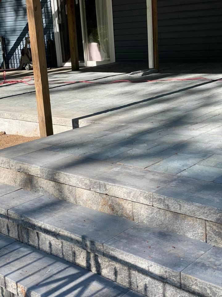Stone steps leading up to a patio area with a wooden support beam.