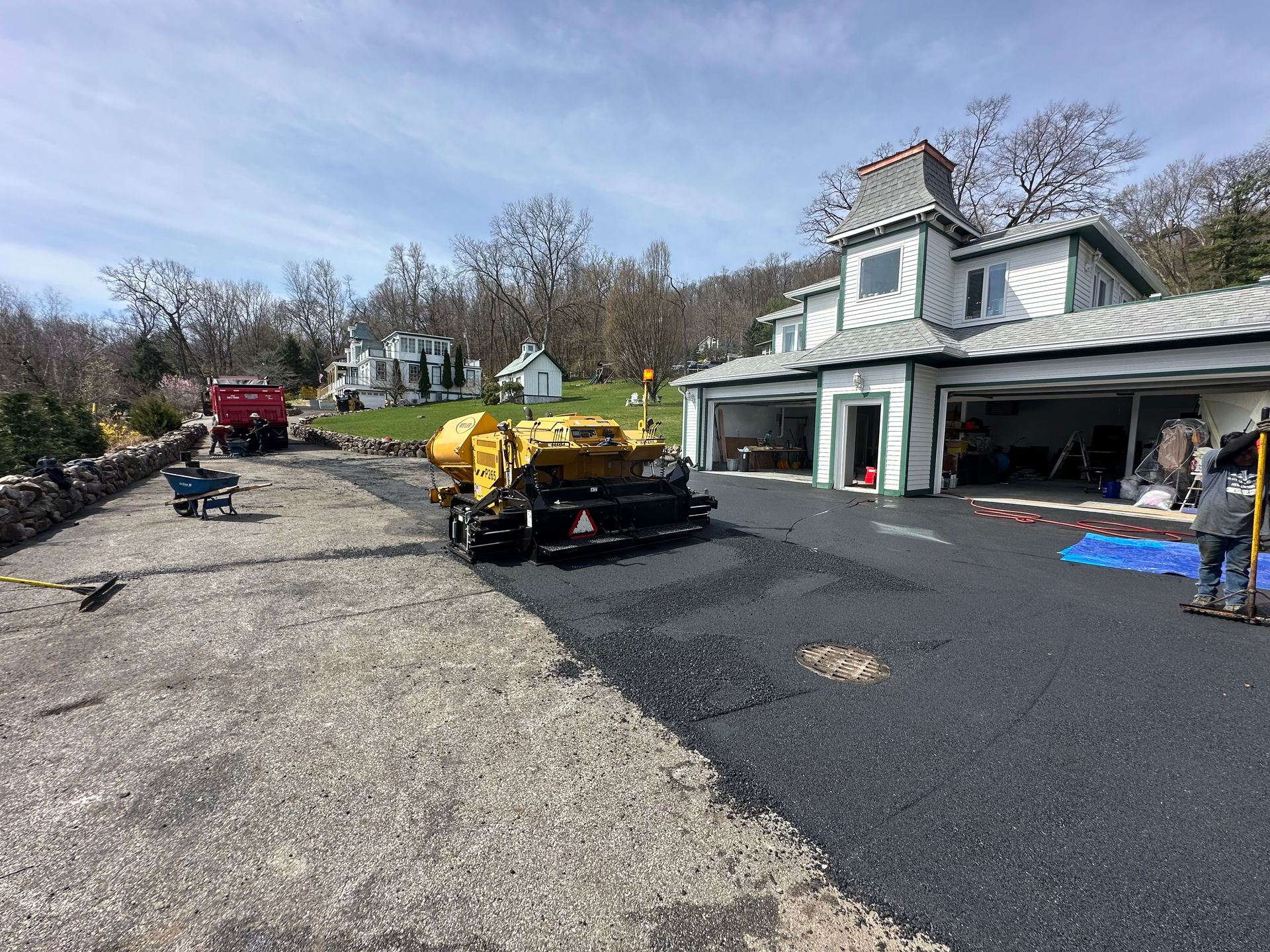 Asphalt paving a driveway next to a white house with an attached garage.