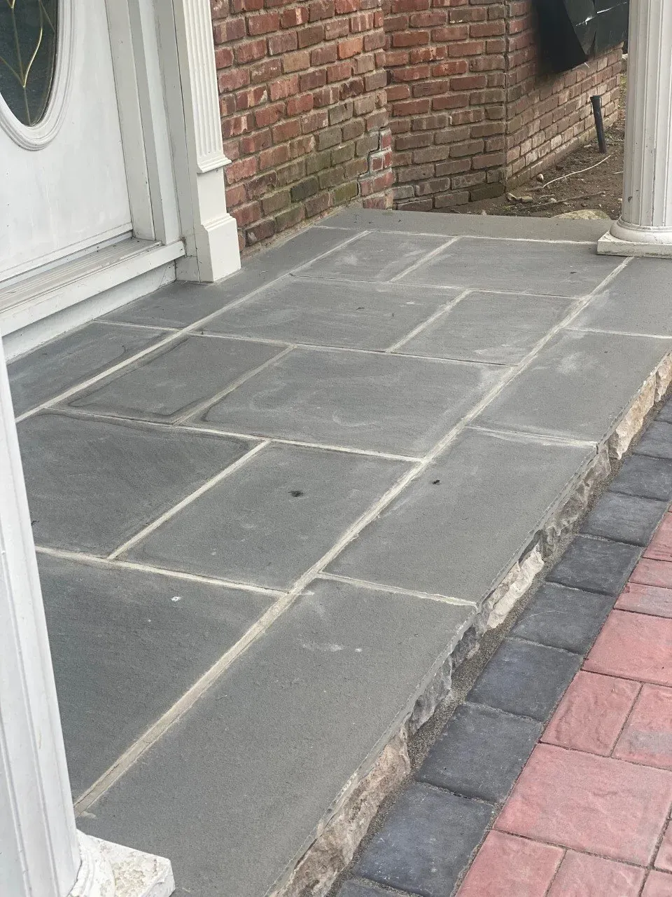 Stone front porch with brick wall background and decorative stone edging.