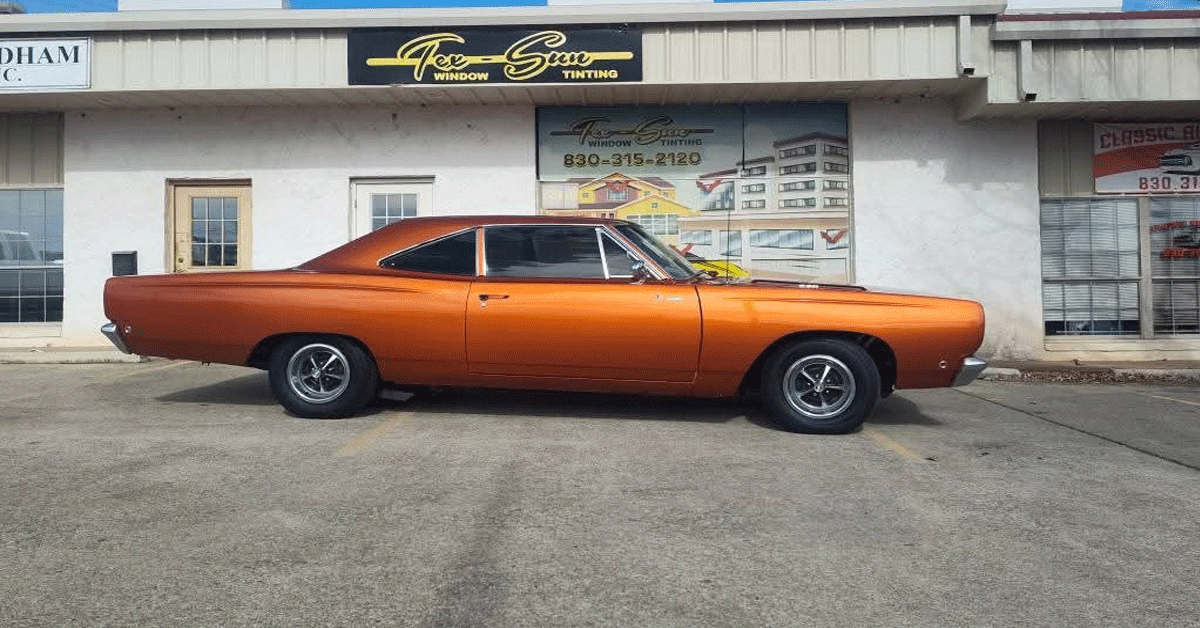 An orange car is parked in front of a building.