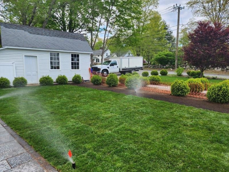 A sprinkler is spraying water on a lush green lawn in front of a house.