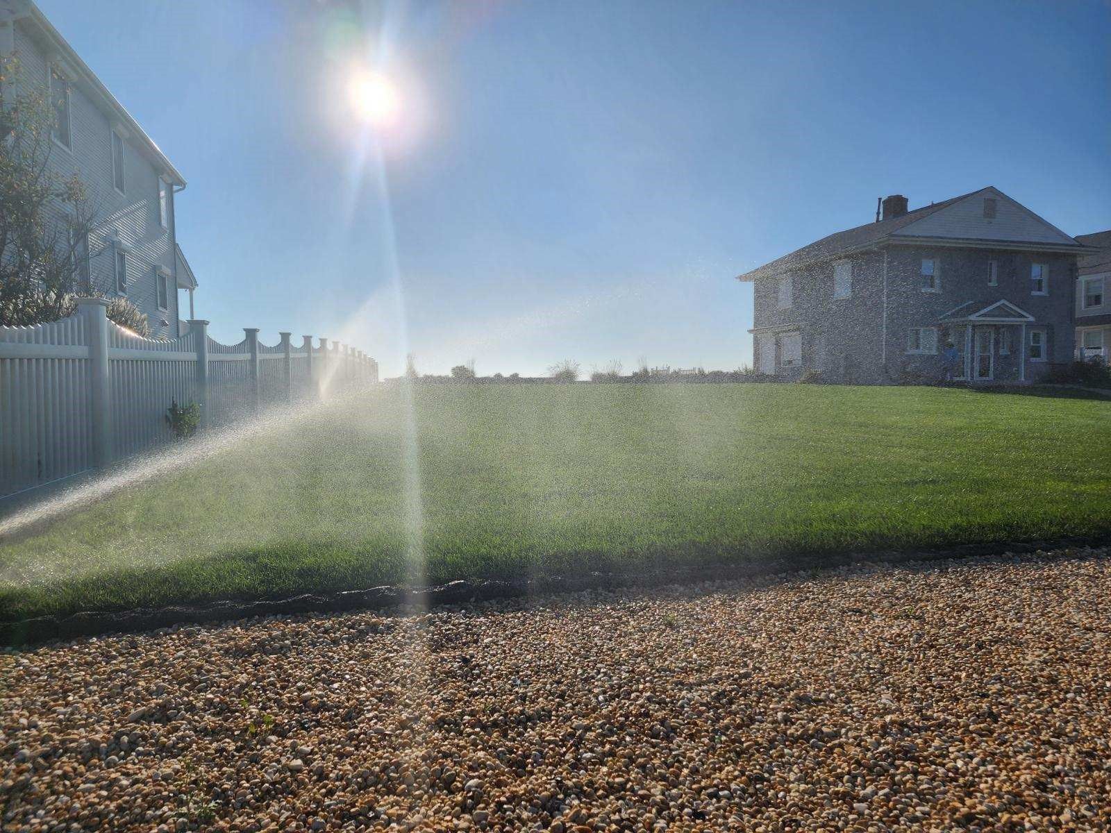 A lawn sprinkler is spraying water on a lush green lawn.