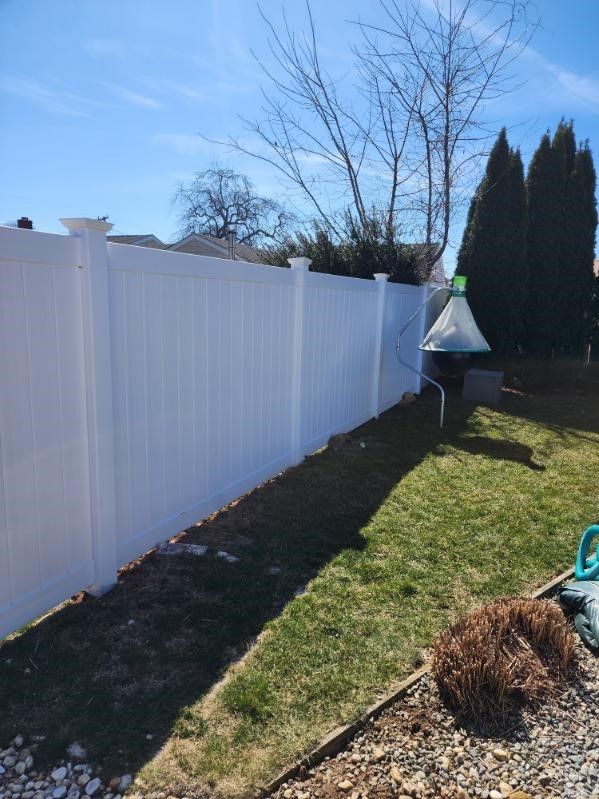 A white fence is surrounding a lush green yard.