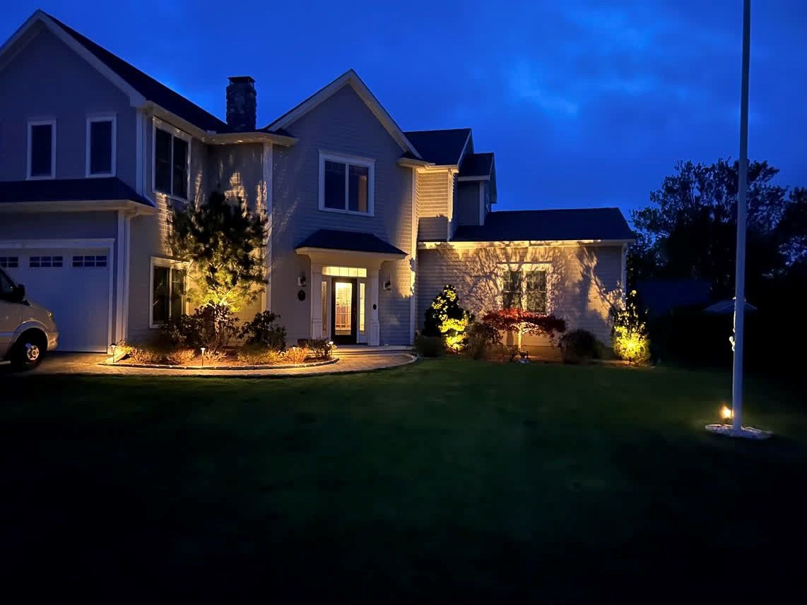 A large house is lit up at night with a truck parked in front of it.