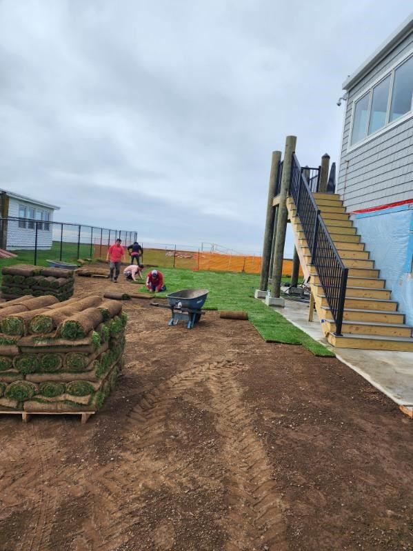 A group of people are working on a lawn in front of a building.