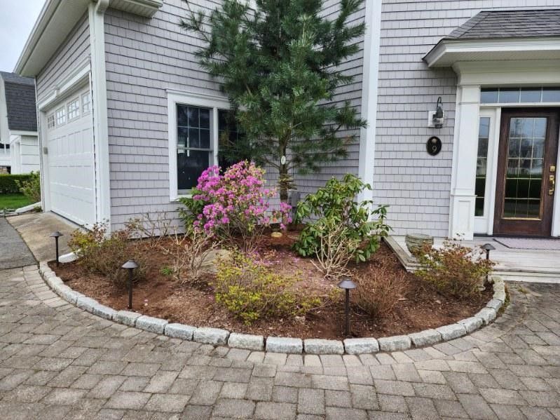 A house with a circular garden in front of it.