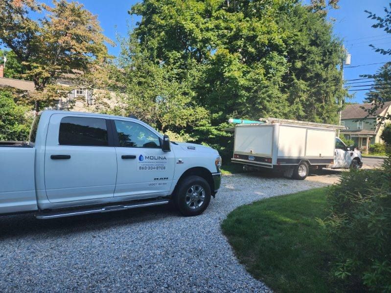 A white truck is parked in a driveway next to a white truck.