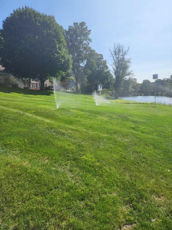 A sprinkler is spraying water on a lush green field.