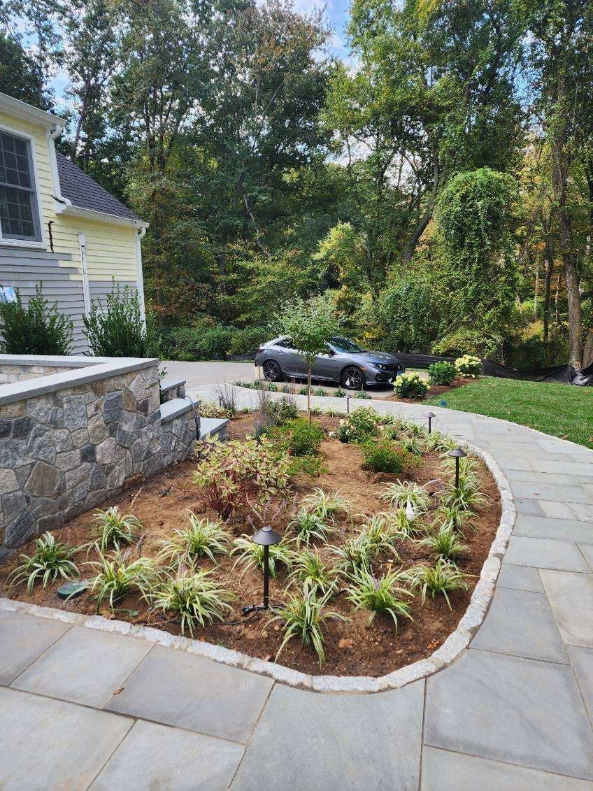 A car is parked in a driveway next to a stone wall.