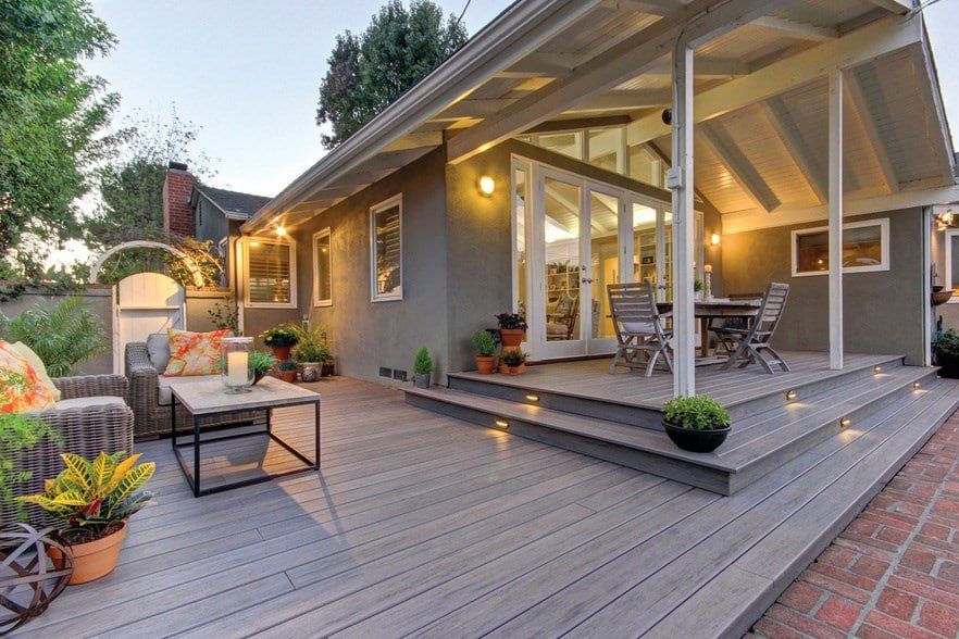 Modern house patio with gray deck, outdoor seating, string lights, and warm evening lighting