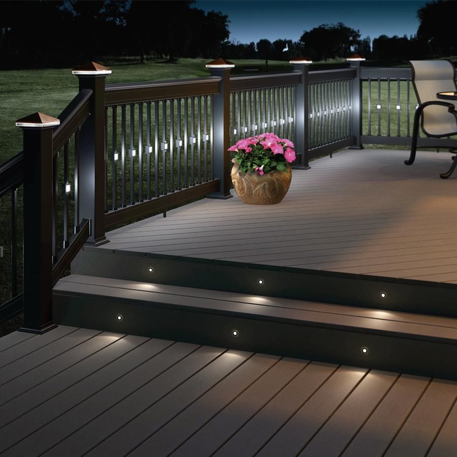 Deck steps with built-in lights, railing, and a potted pink flower at dusk