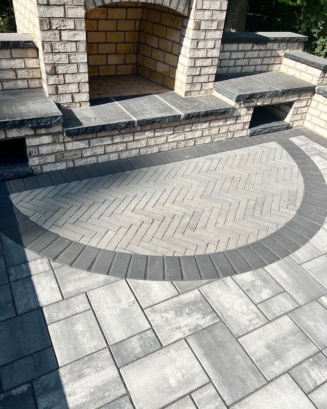 Outdoor stone patio with circular paver inlay and brick fireplace nook