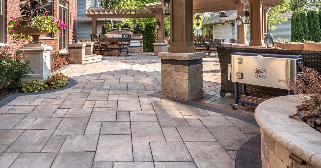 Stone patio with pavers, benches, planters, and pergola in a landscaped courtyard