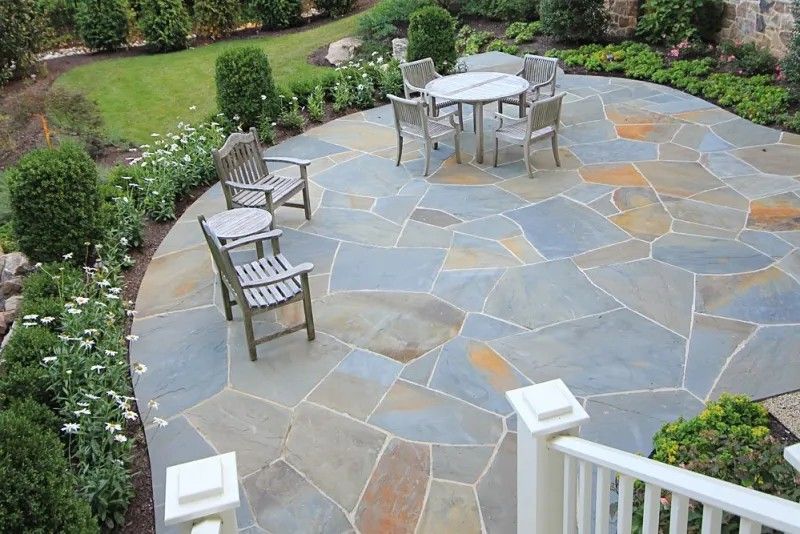 Stone patio with table and chairs in a landscaped garden