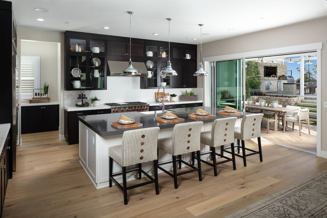 Modern kitchen with a large island, dark cabinets, and sliding doors to an outdoor dining area.