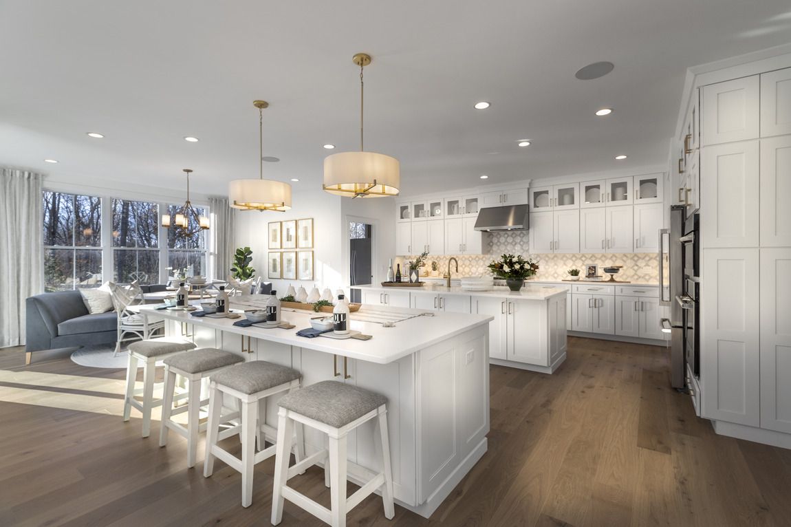 Spacious white kitchen with island, breakfast bar, and open layout to living area with large windows and a view.