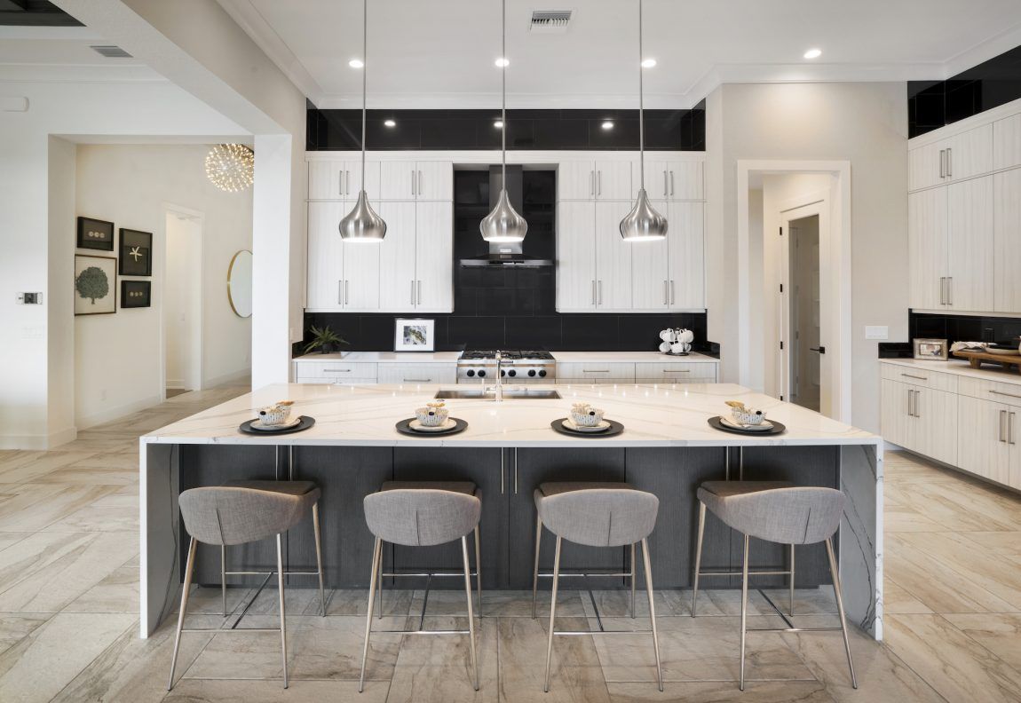 Modern kitchen with large island, white cabinets, gray accents, and four bar stools.