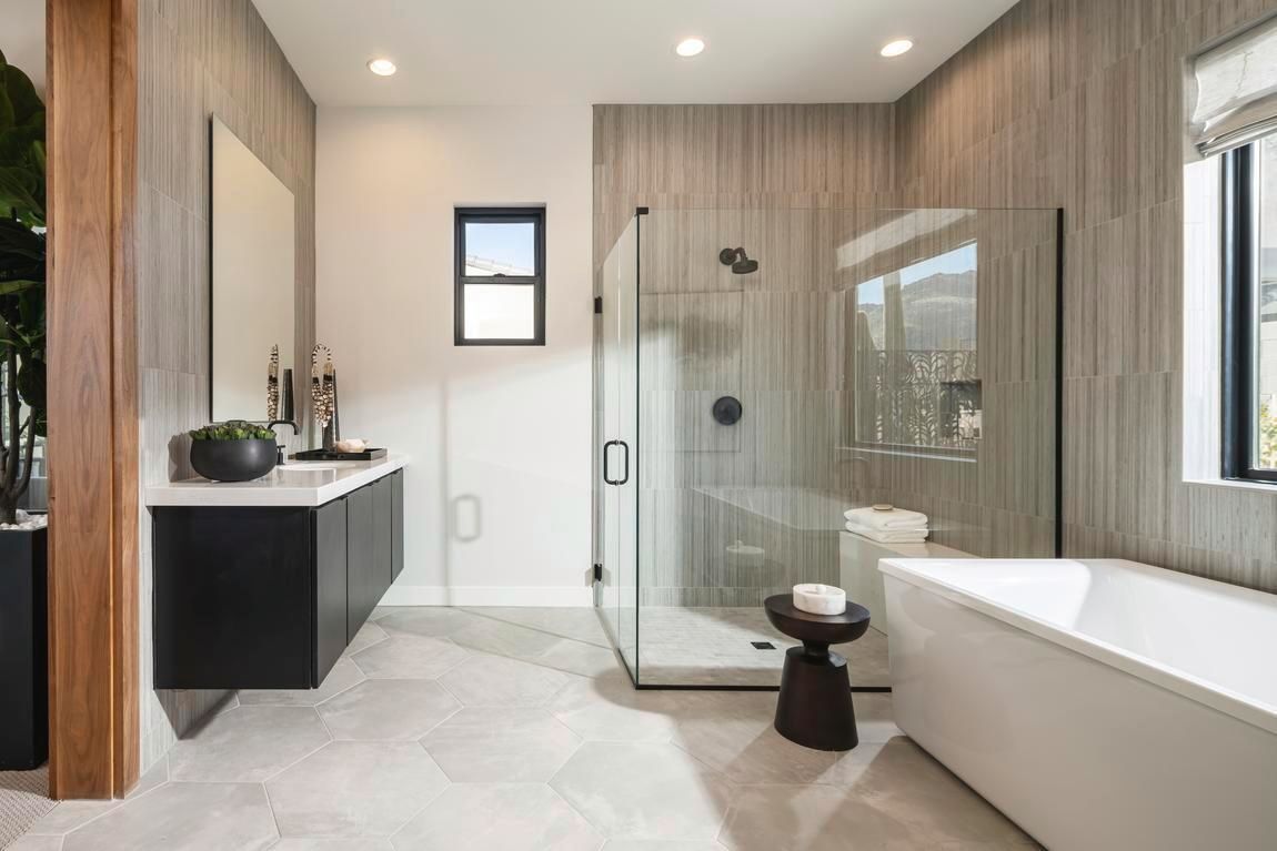 Modern bathroom with a glass shower, soaking tub, floating vanity, and grey tile.
