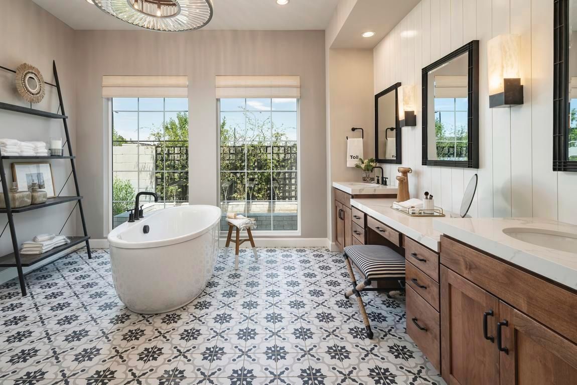 Bathroom with patterned tile floor, freestanding tub, dual vanities, windows, and ladder shelf.