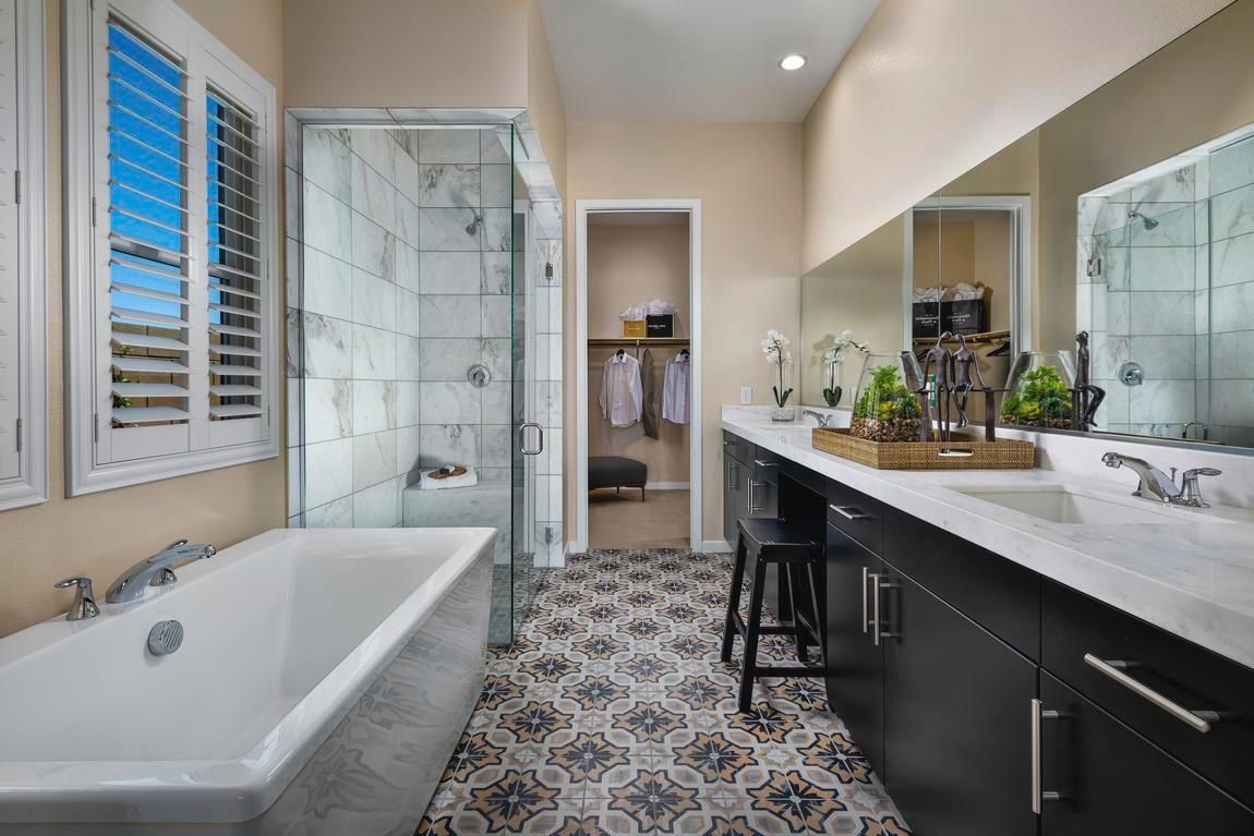Bathroom with bathtub, shower, vanity, patterned floor, and walk-in closet.